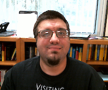 Headshot of Joe Torres in front of office bookshelves and a window