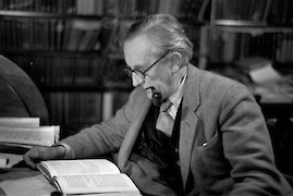 photo of J.R.R. Tolkien (with pipe) reading in a library